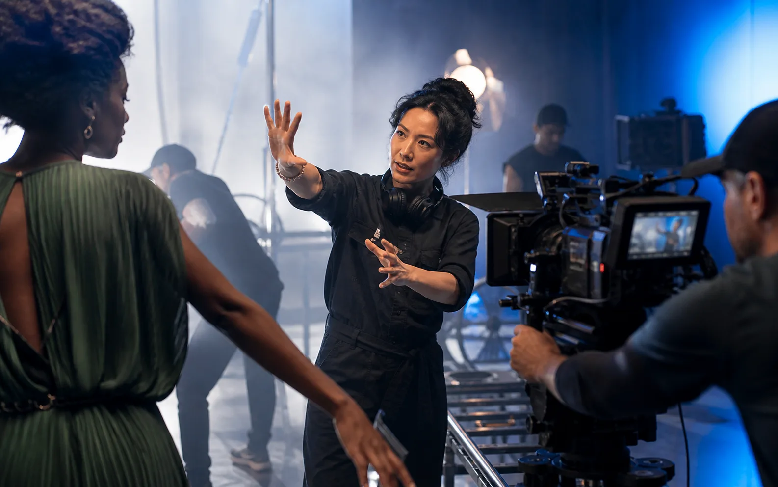 A film director guiding a performer and camera crew on a cinematic set